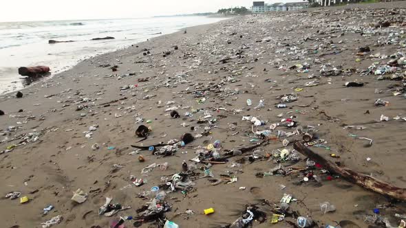 Camera moves fast over plastic trash on the beach, polluted ocean threatens life under water