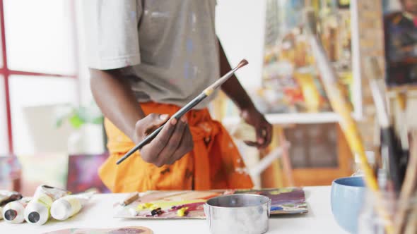 Midsection of african american male painter painting on canvas in artist studio