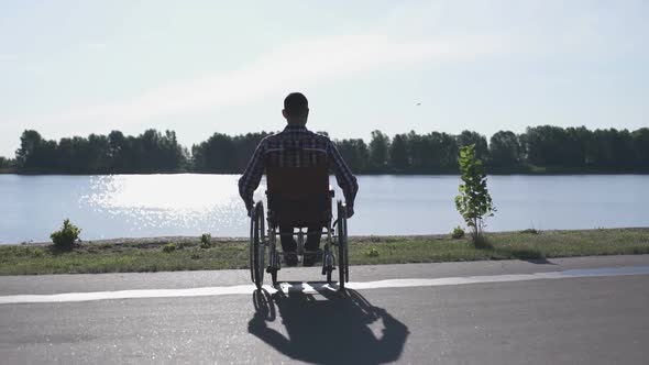 A Man in a Wheelchair Walks on the Waterfront