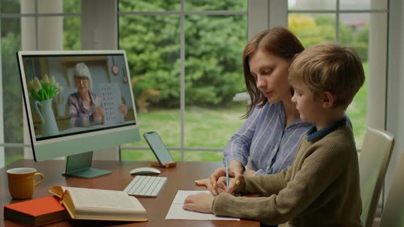 Young 30s Mother Helping Her Son with Online Lesson at Home