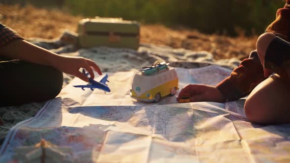 Close up shot of two children playing with different toys on a map at golden hour