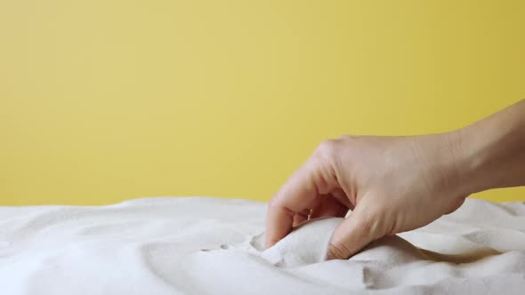 Woman's Hand Scoops Up and Sprinkles White Sand on Yellow Studio Background