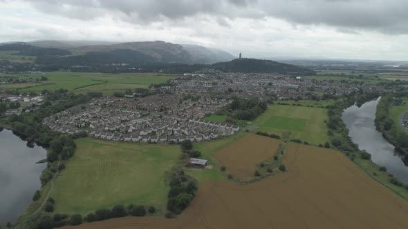 high aerial shot over Stirling flying east, towards the Wallace Monument on a cloudy day