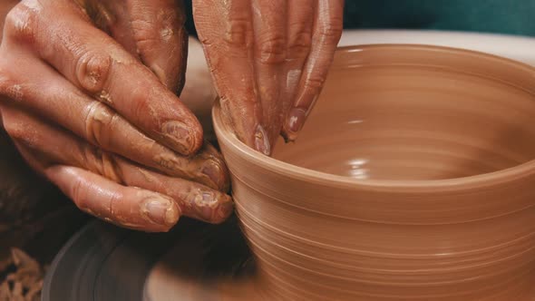 Man's Hands Sculpting the Sides From a Pot Out From the Clay on a Potter Wheel