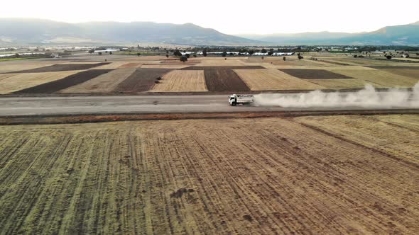 Aerial Footage Large White Truck with Truck Loaded with Rocks is Driving Down Gravel Road with Dust