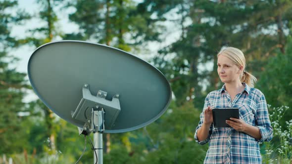 Woman Sets Up a Satellite Dish, Uses a Tablet