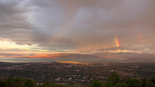 Sunrise stormy time lapse as rainbow forms over city in Utah