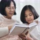 Happy Asian grandmother and lovely girl reading book together. - VideoHive Item for Sale