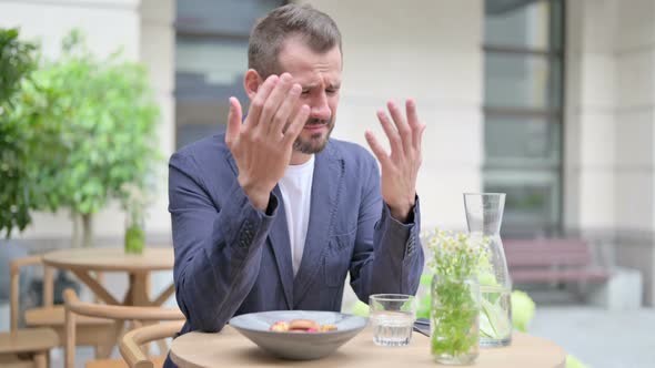 Upset Man Worried While Sitting in Outdoor Cafe