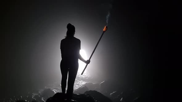 Young woman with torch in cave facing the sea. It is called Cueva del Guincho, located in the city o