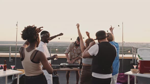 Man DJing and People Dancing on Rooftop Terrace