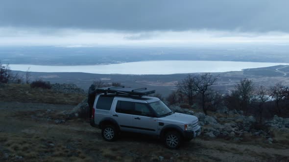 Young man opening hardcover rooftop tent on silver truck in mountains