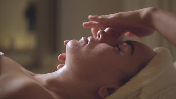 Young Beautiful Caucasian Woman Lying on Spa Bed Get Facial Massage Treatment with Aroma Essential