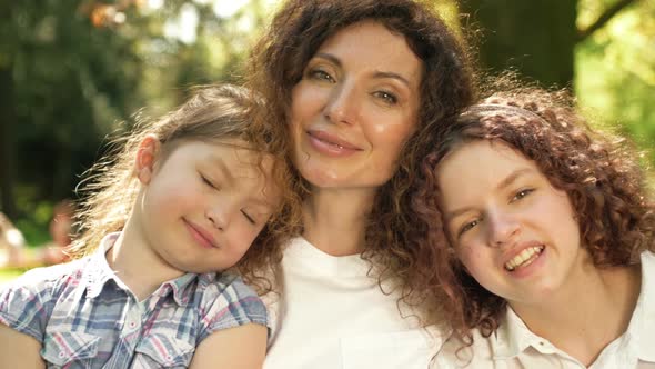 Happy Woman Hugs Two Daughters of Different Ages