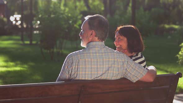Happy Senior Couple Sitting on Bench at Park