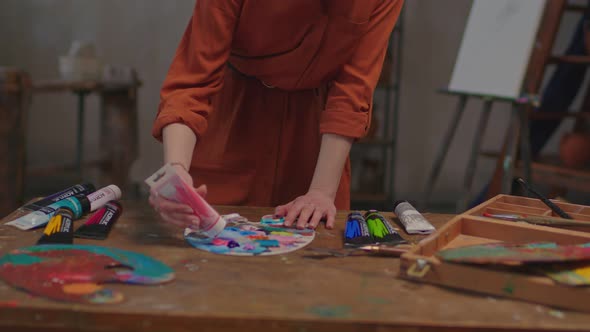 Woman Painter Squeezing Paint Tube on Colorful Palette