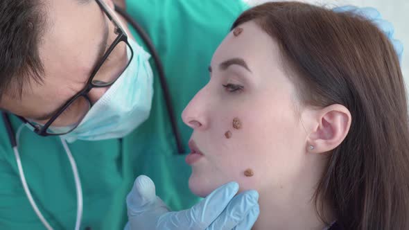 Doctor Examines a Young Woman with Large Moles on Her Face Close Up