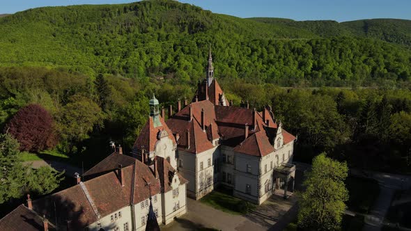 A beautiful old European castle among the green mountains. Shooting from a bird's-eye view.
