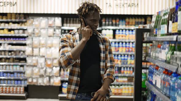 Handsome Man Using Smartphone Pushes Shopping Cart Walks at the Store