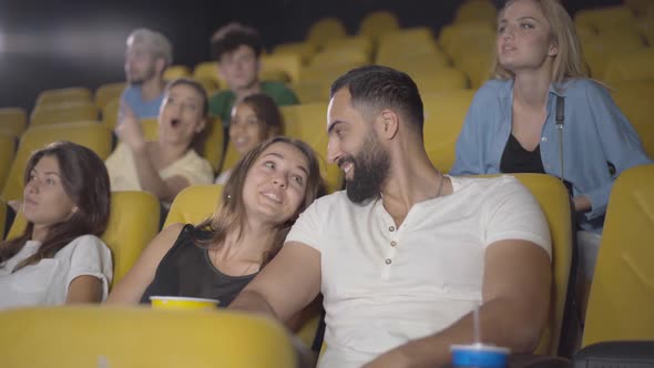 Portrait of Cheerful Young Caucasian Woman Dating with Handsome Middle Eastern Man in Cinema