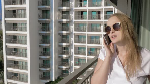 Cheerful woman having mobile phone talk on the balcony