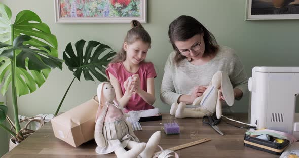 Happy Mother and Daughter Sewing Together Toy Bunny Doll at Home