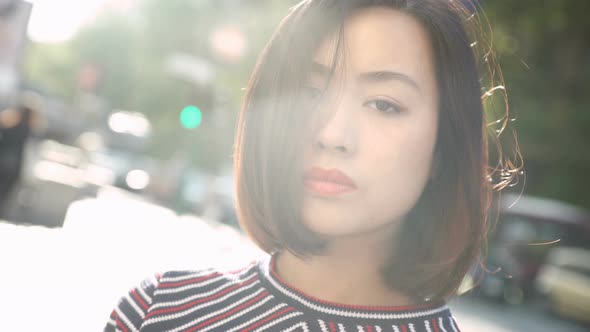 young chinese woman standing, looks upset. Woman in the city sunset