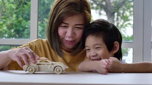 Asian Mother And Son Playing Wood Toy Car Together
