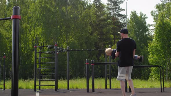 Young Caucasian Father Having Fun with Son at Outdoor Gym