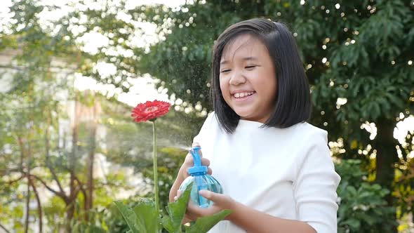 Beautiful Asian Girl Watering A Red Flower In The Garden