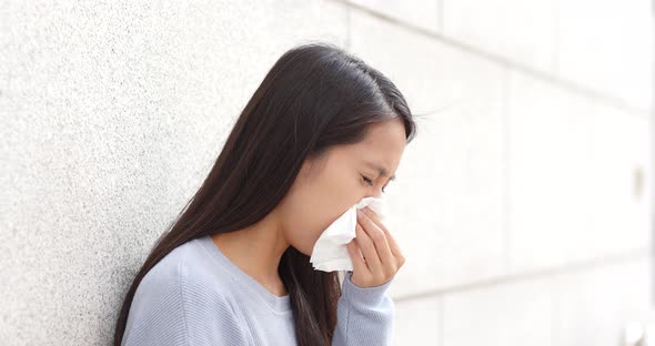 Woman sneezing at outdoor