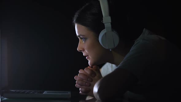 Nervous Girl in Headset Watching Online Betting Site at Night Eager to Win