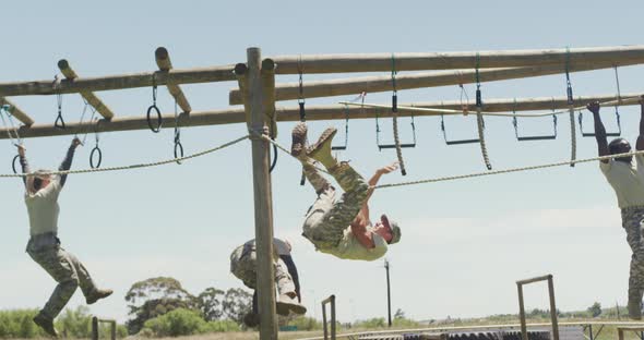 Fit diverse group of soldiers using hanging rope and rings on army obstacle course in the sun