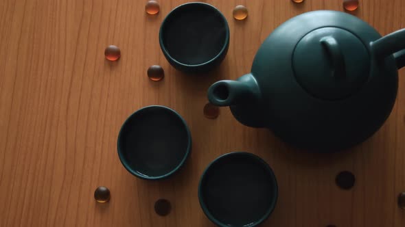 minimal background of a green japanese tea set with steam coming out of the cups, on a wooden table,