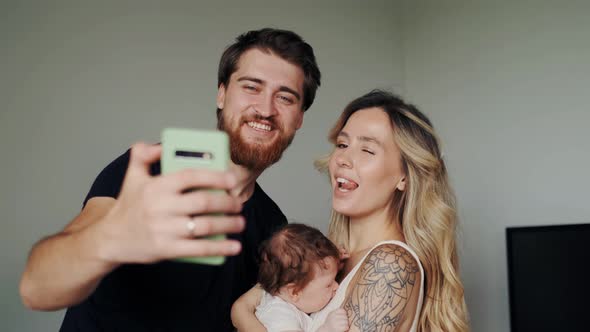 Happy Mother Father and Little Sweet Baby Having Video Chat Using Smartphone Indoor in Cozy Kitchen
