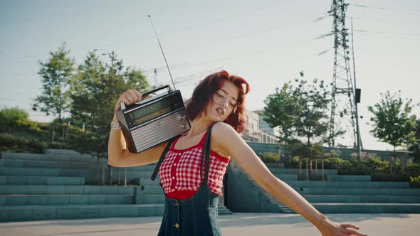 Young Beautiful Pin Up Woman with Retro Radio Receiver Riding on Squads in Parkdancing with Music