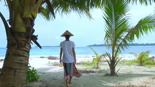 Slow motion: woman walking on sunny tropical beach caribbean sea palm trees turq