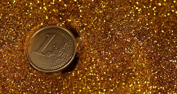 Coin of 1 Euro falling on Gold Powder against Black Background, Slow motion 4K