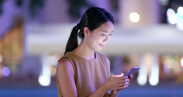 Woman use cellphone in city at night