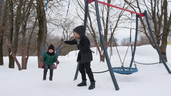 Mom Swings Her Son on a Swing