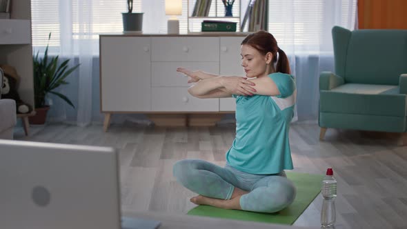 Woman in Sportswear Leads a Sporty Lifestyle and Exercises with an Online Instructor While Sitting
