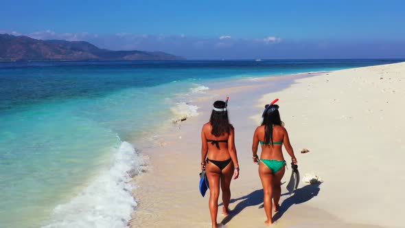 Beautiful women sunbathing on idyllic coast beach break by transparent ocean and white sand backgrou