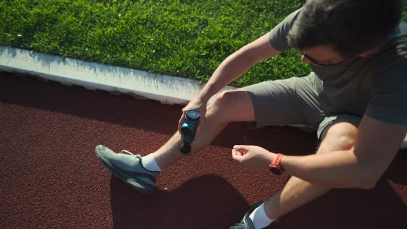 An Athlete Massages with a Percussion Therapy Gun to Relieve the Pain of Muscle Aches After a