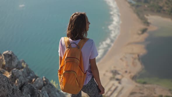 Rear View Happy Girl Stands on Edge of High Cliff Enjoying Beautiful Seascape of Aegean Coastline