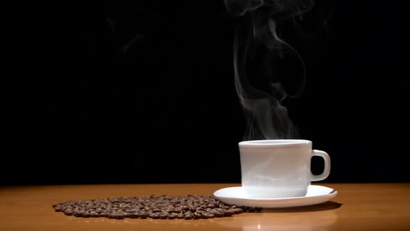 Hot Coffee Cup and Beans on Wooden Table, Black Background.