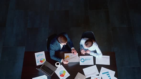 Young people in suits discussing charts and profits in the company