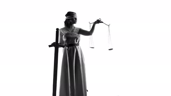 Young Woman Disguised As Goddess of Justice Stands Leaning on Sword with One Hand and Holding Scale