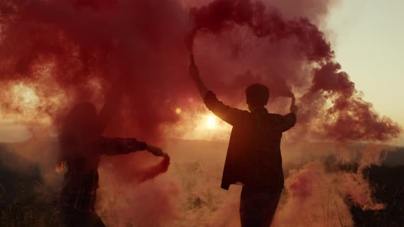 Woman and Man Waving Hands with Colorful Smoke Grenades