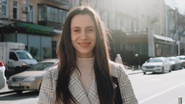 Portrait of a Young Smiling Woman on the Street in Sunny Day