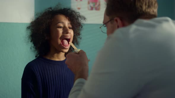 Doctor Using Depressor Checking Girl Throat Closeup